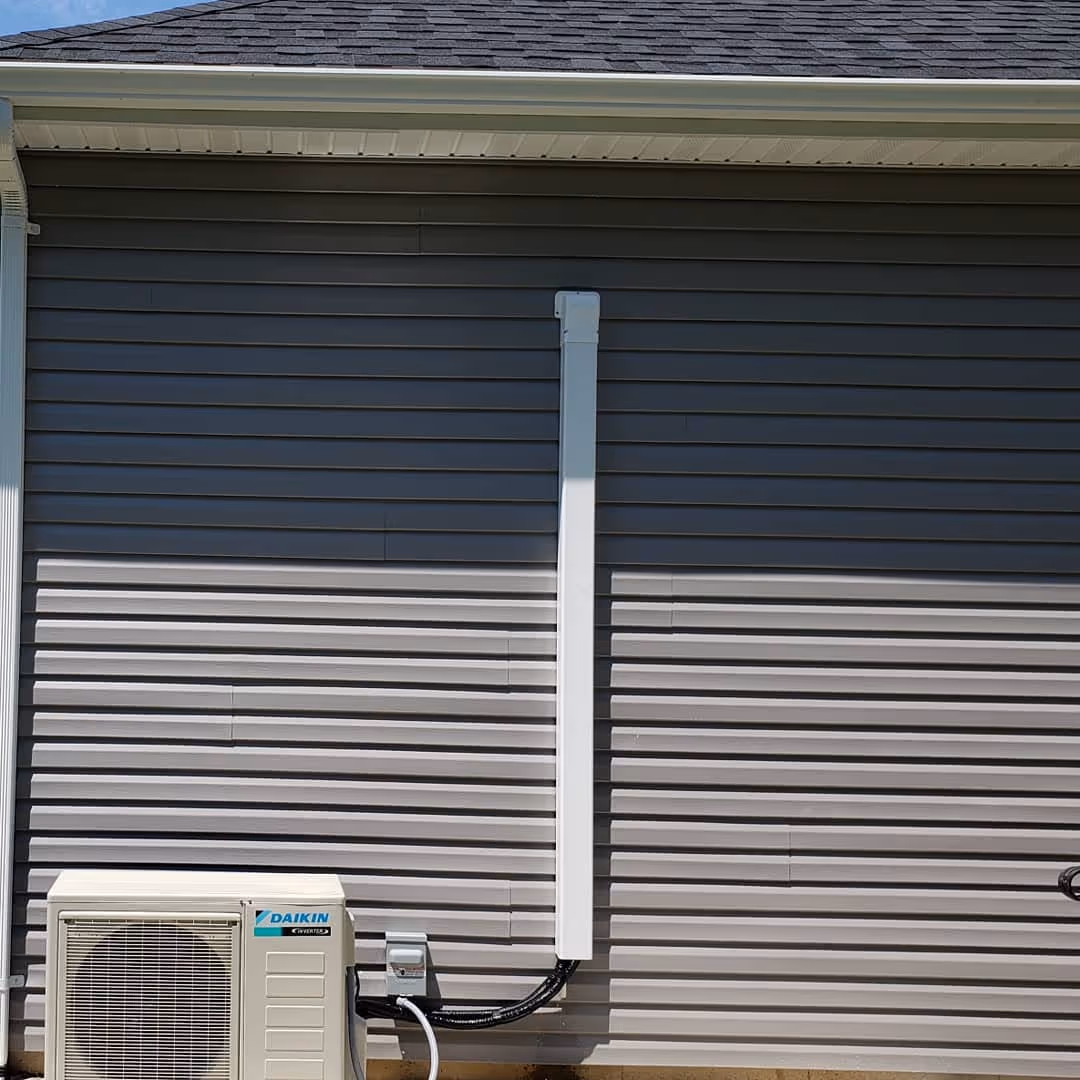 Daikin air conditioning unit mounted on gray siding near roof