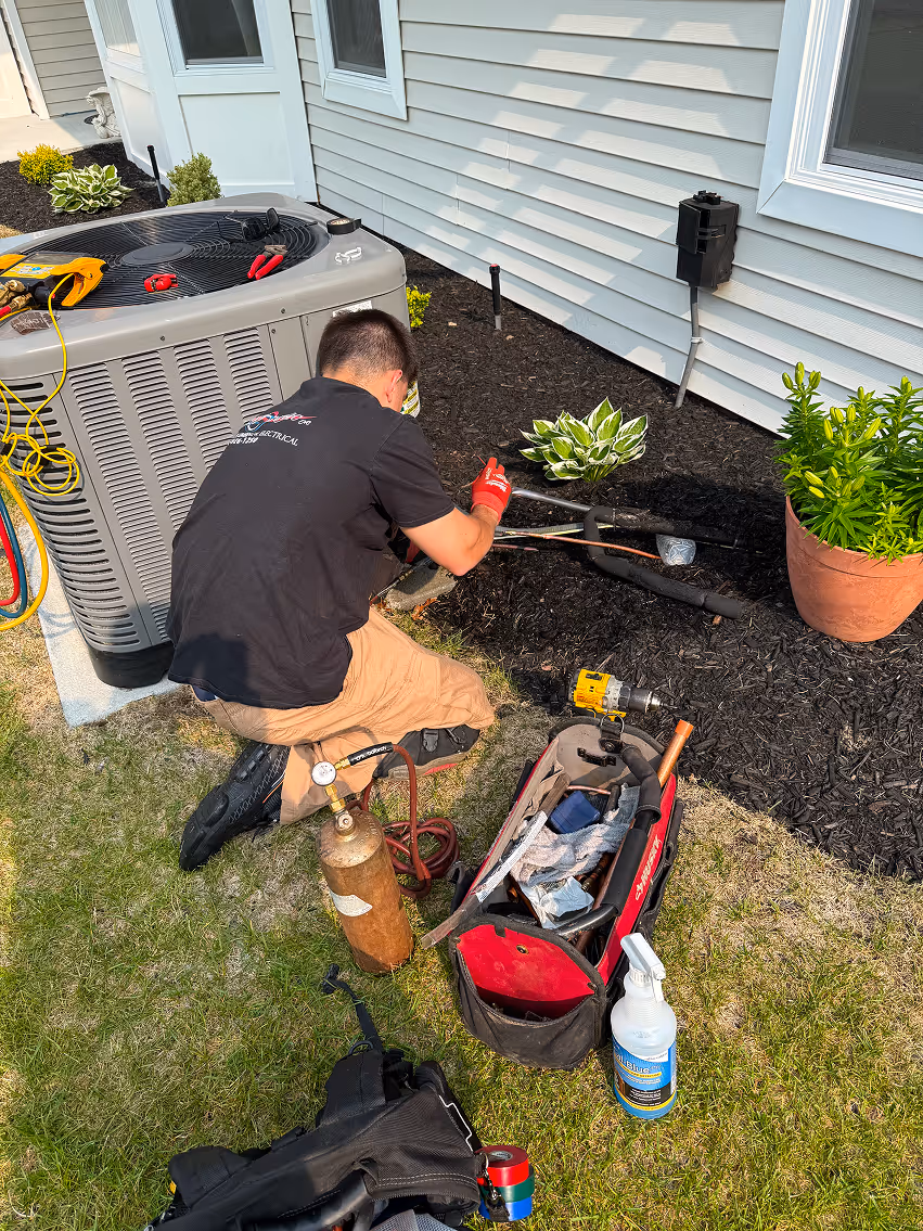 Technician repairing air conditioning unit outside residential home