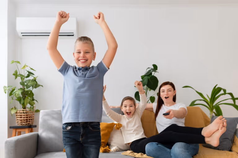 Family celebrating with raised arms and excitement while watching TV together