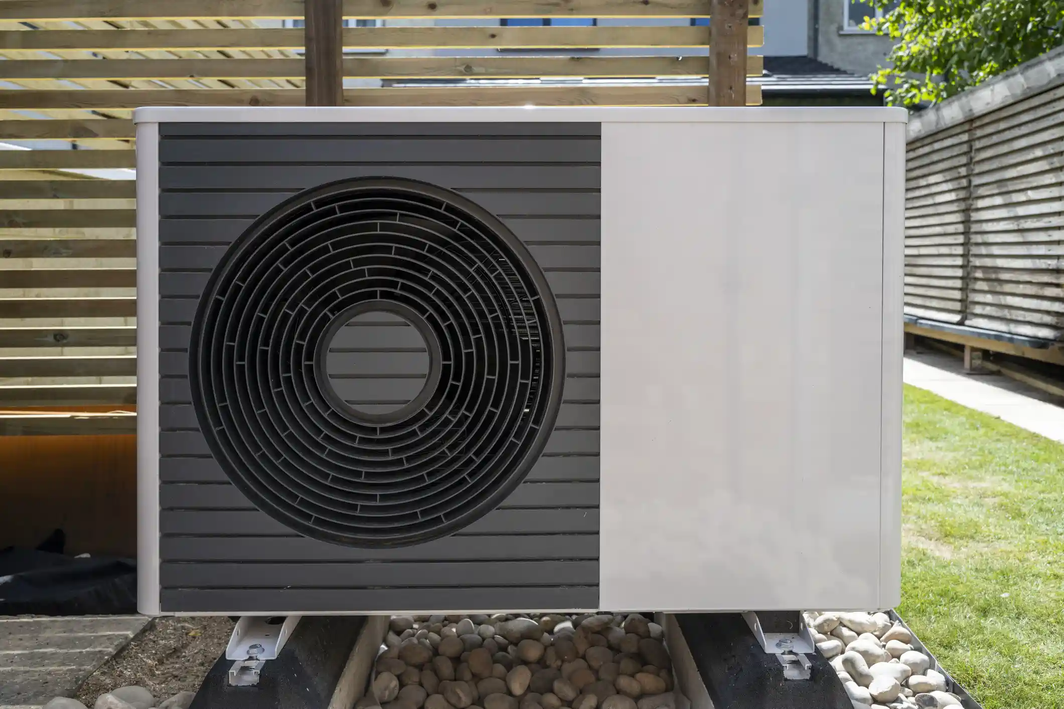Modern heat pump unit installed outdoors with circular ventilation grille