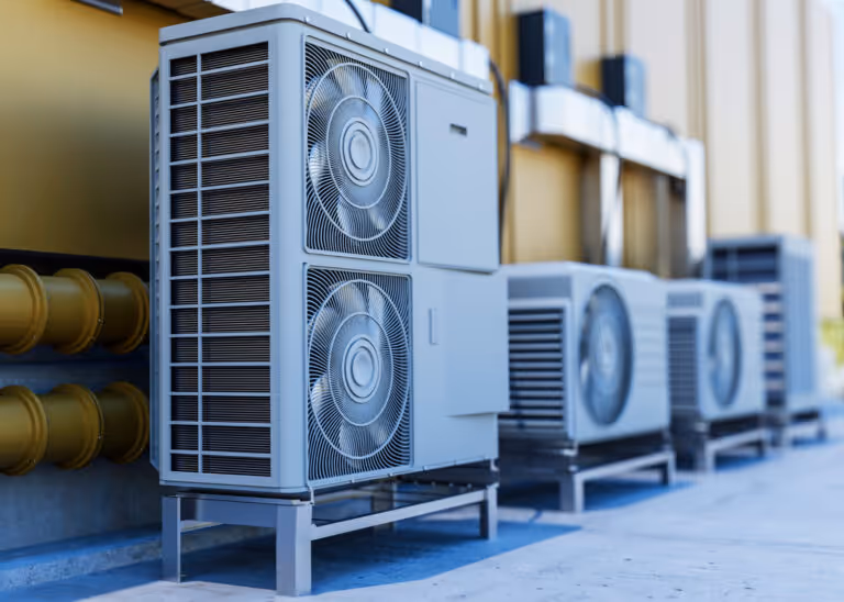 Multiple air conditioning units installed outside a building with metal fans