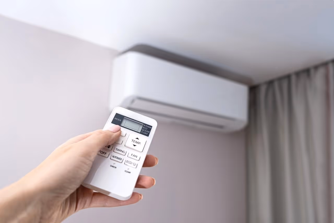 Hand holding remote control for wall-mounted air conditioning unit