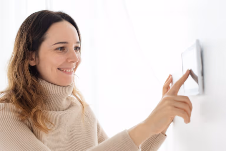 Woman in cozy turtleneck sweater touching wall with gentle smile