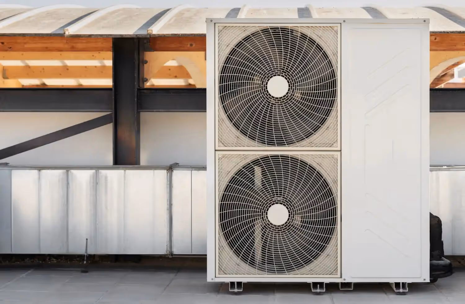 Large white air conditioning unit with two fans mounted on building exterior