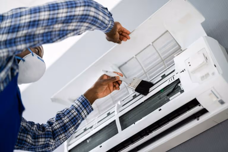 Technician in plaid shirt installing or repairing a wall-mounted air conditioner