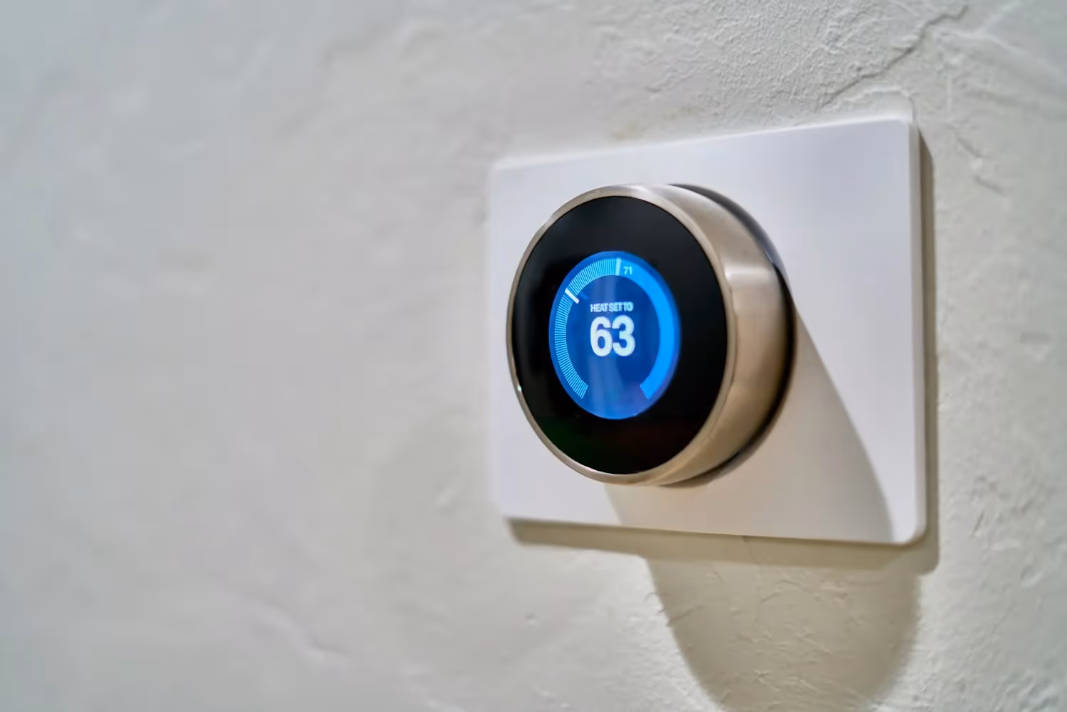 Smart thermostat with blue screen showing heat set to 63 degrees