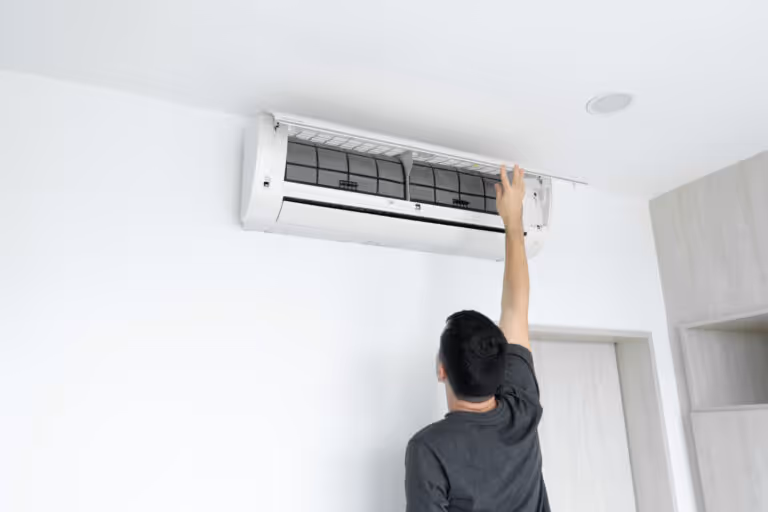 Person adjusting air conditioning unit mounted on white wall