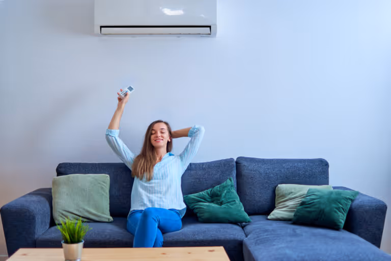 Woman relaxing on couch, holding remote, enjoying air conditioning