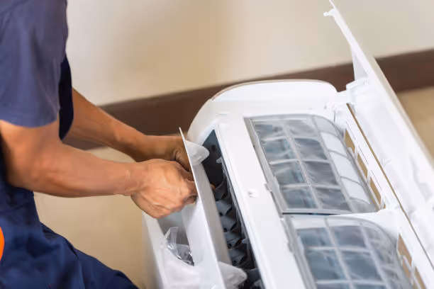 Technician repairing or maintaining an air conditioning unit's filter