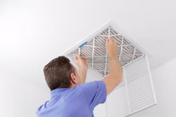 Person removing air filter from ceiling vent for home maintenance