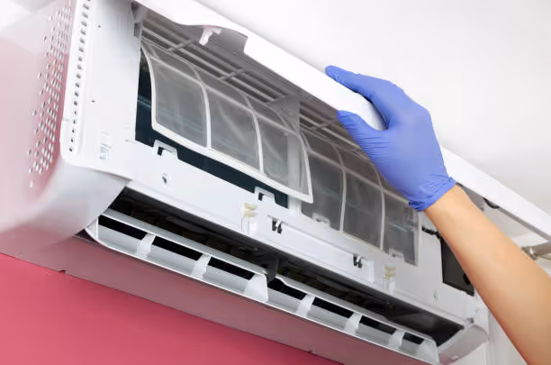 Gloved hand cleaning air conditioning unit filter
