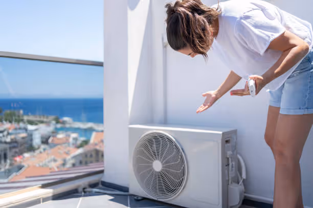 Person checking outdoor air conditioning unit with ocean view