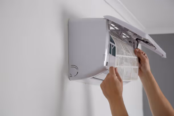 Hands adjusting filter on a wall-mounted air conditioning unit