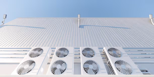 Multiple industrial air conditioning units on a white building exterior
