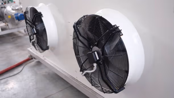 Large industrial fans mounted on white housing in mechanical room