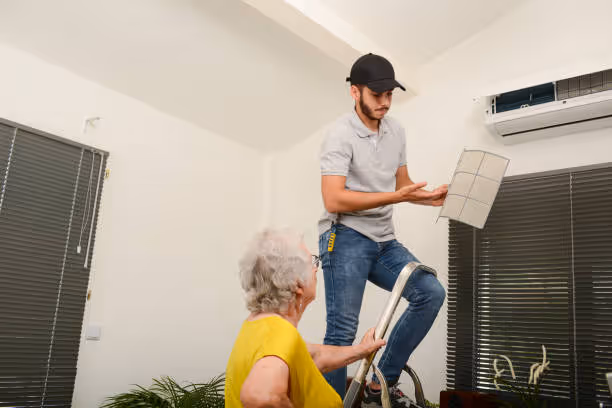 Technician installing air conditioner unit for elderly woman at home