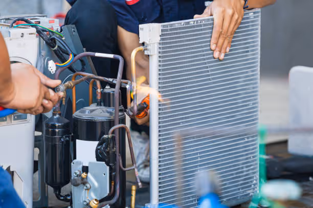 Technician repairing air conditioning unit, examining compressor and condenser