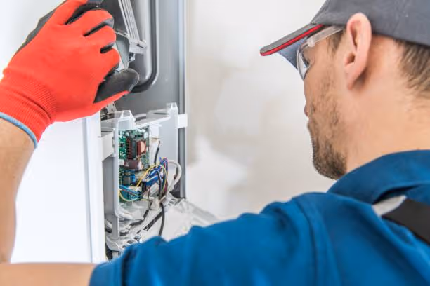 Technician in blue uniform repairs electrical panel with red protective gloves