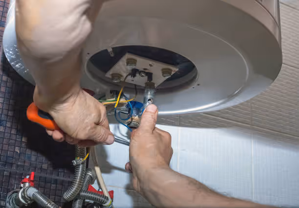 Technician repairing electrical connections inside an electric water heater