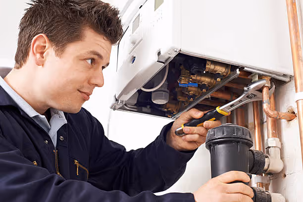 Technician repairing a boilers internal components with a wrench