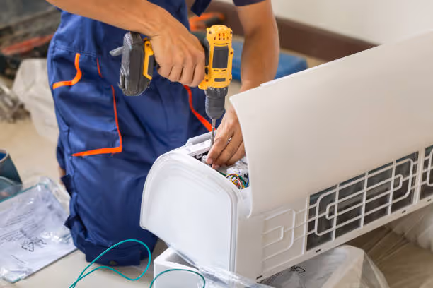 Technician repairing air conditioner with yellow power drill