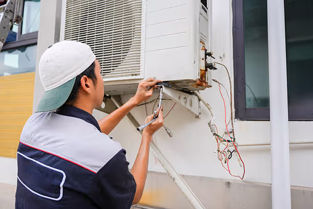 Technician repairing air conditioning unit with tools and wiring