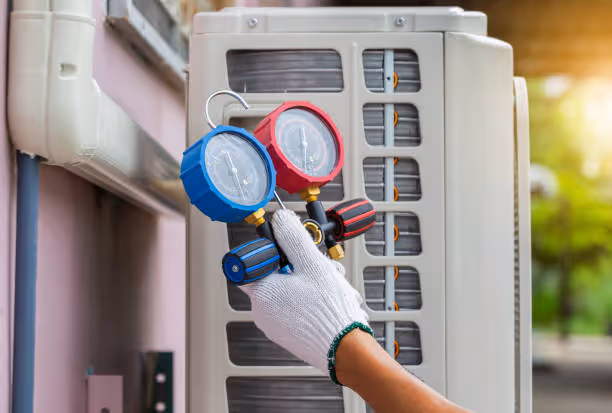 Technician checking air conditioner pressure with blue and red gauges