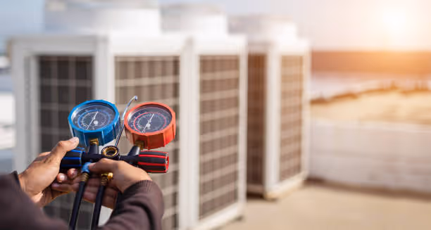 Technician using pressure gauges to check HVAC system near solar panels