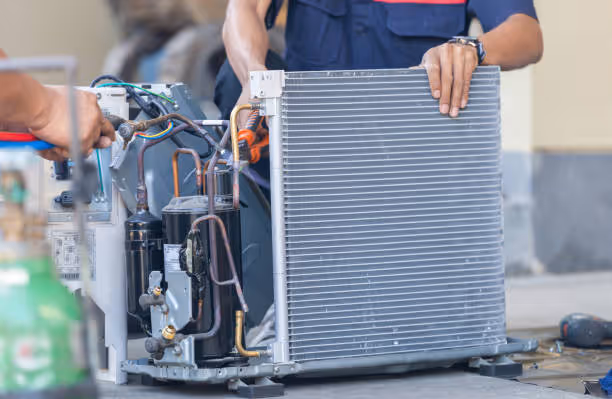 Technician repairing air conditioning unit with large condenser coil