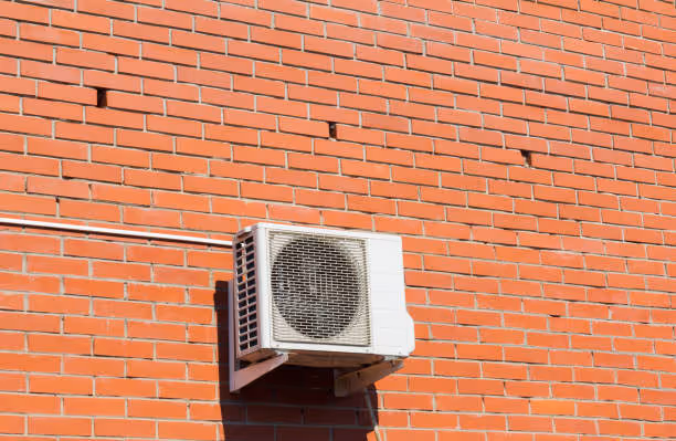 White air conditioning unit mounted on orange brick wall