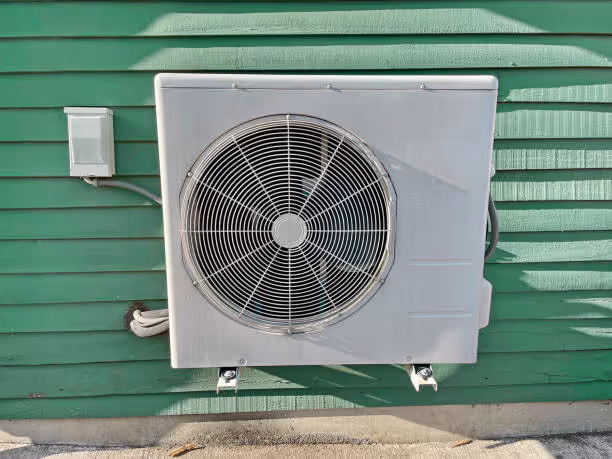 Outdoor air conditioning unit mounted on green wooden siding