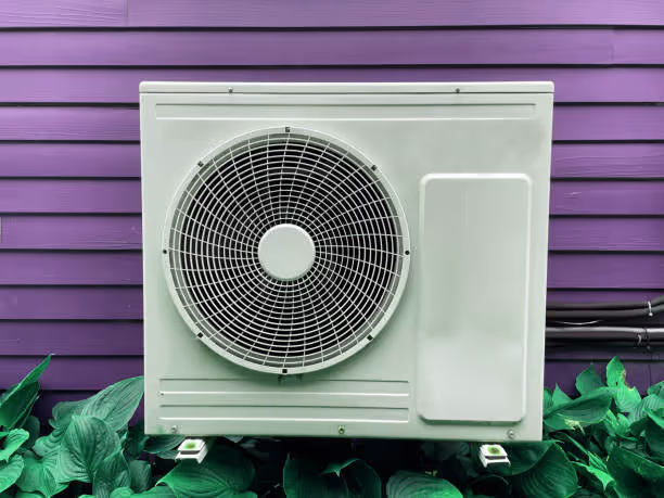White air conditioning unit mounted on purple wall surrounded by green plants
