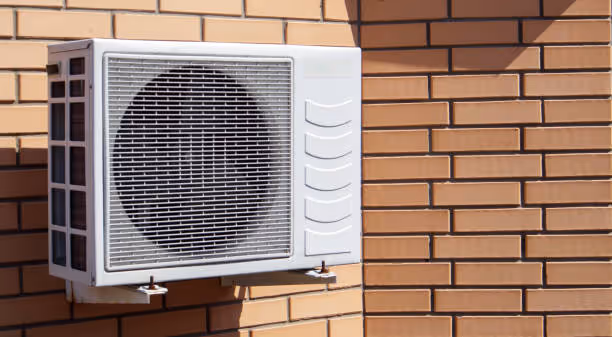 White air conditioning unit mounted on brown brick wall exterior