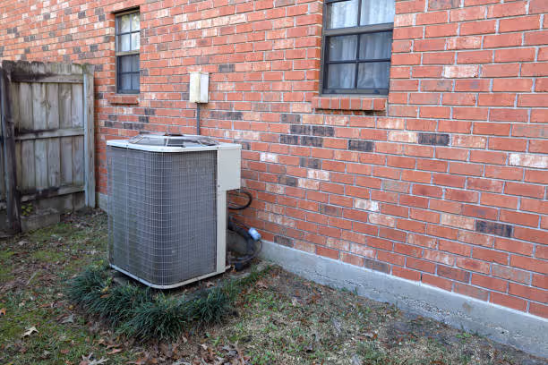 Air conditioning unit beside red brick wall and wooden fence