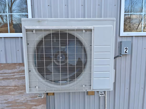 White outdoor air conditioning unit mounted on metal building wall