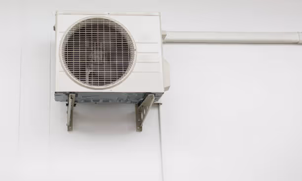 White air conditioning unit mounted on wall with circular ventilation grid