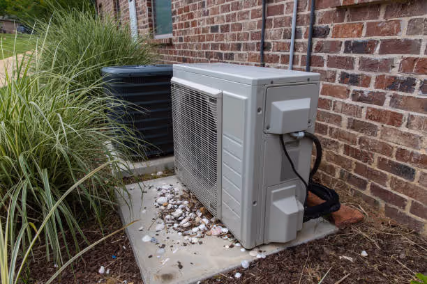 Air conditioning units installed on concrete pad next to brick building