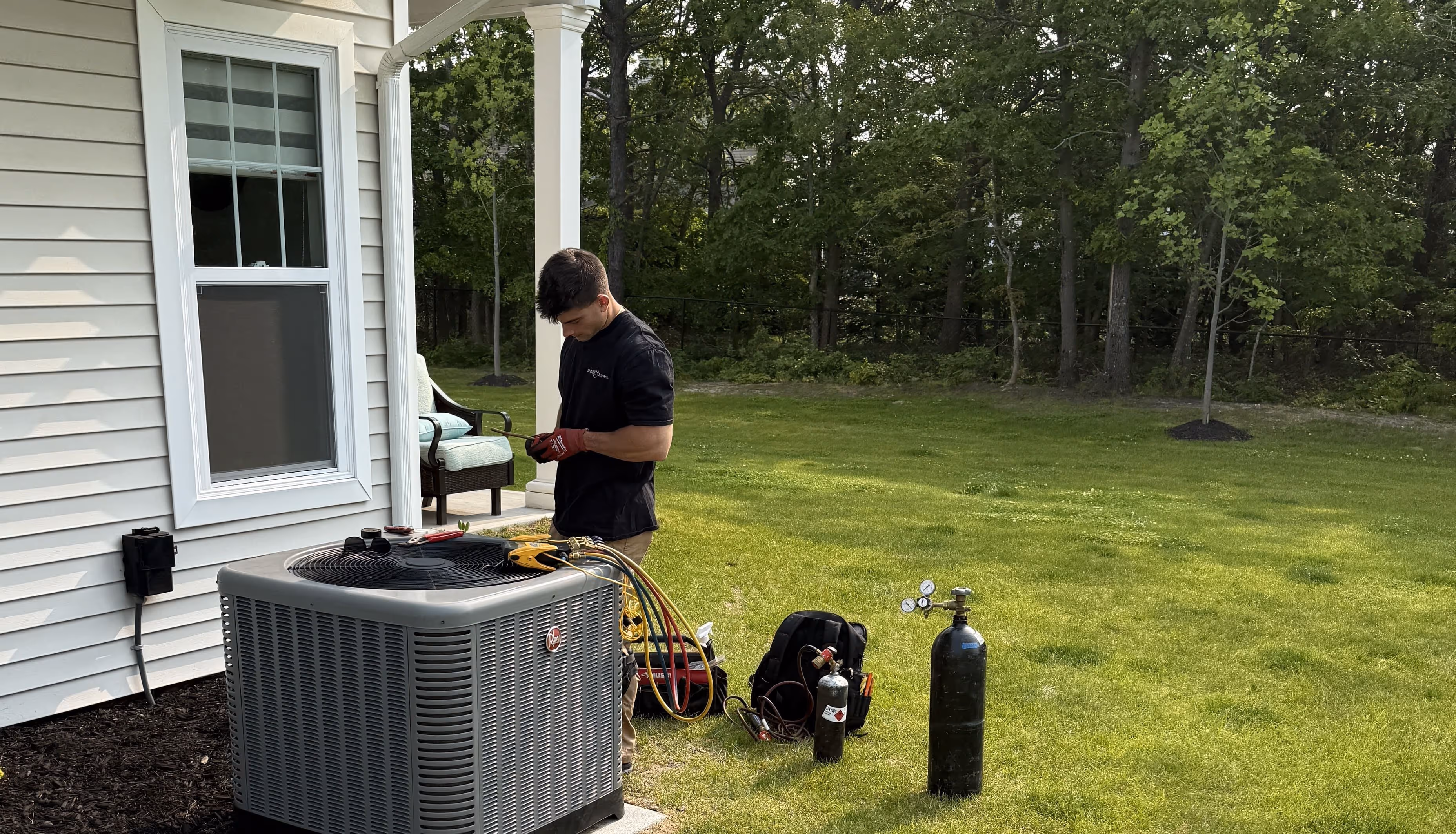 HVAC technician repairing air conditioning unit outside residential home