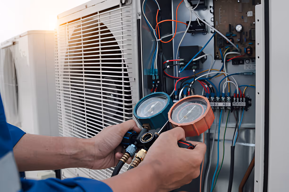 Technician checking air conditioning unit with pressure gauges
