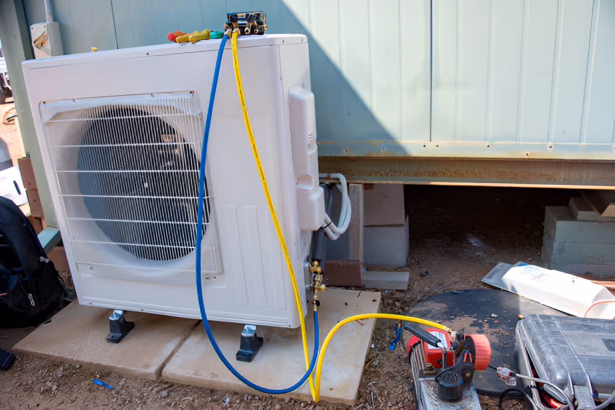 Air conditioning unit with blue and yellow service hoses during installation