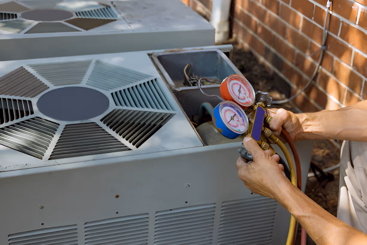 Technician checking air conditioning unit with pressure gauges