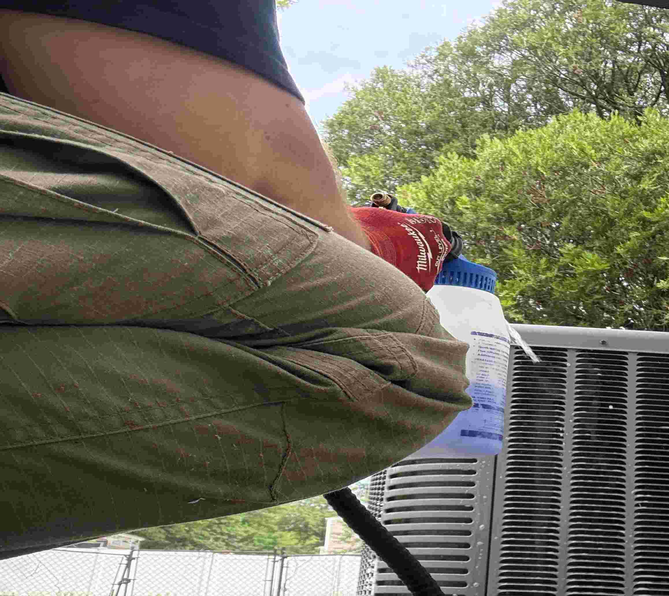 Technician checking HVAC unit outdoors with Milwaukee water bottle nearby