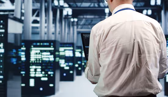 Repairman running code diagnostics in a data center, surrounded by servers and network cables for maintenance.