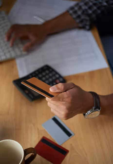 Top view of cropped male hands making an online purchase, paying with a plastic card on a laptop keyboard.