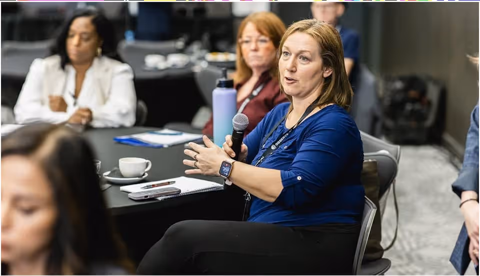 A woman attentively asking questions during a discussion or interview, showing curiosity and engagement in the conversation.