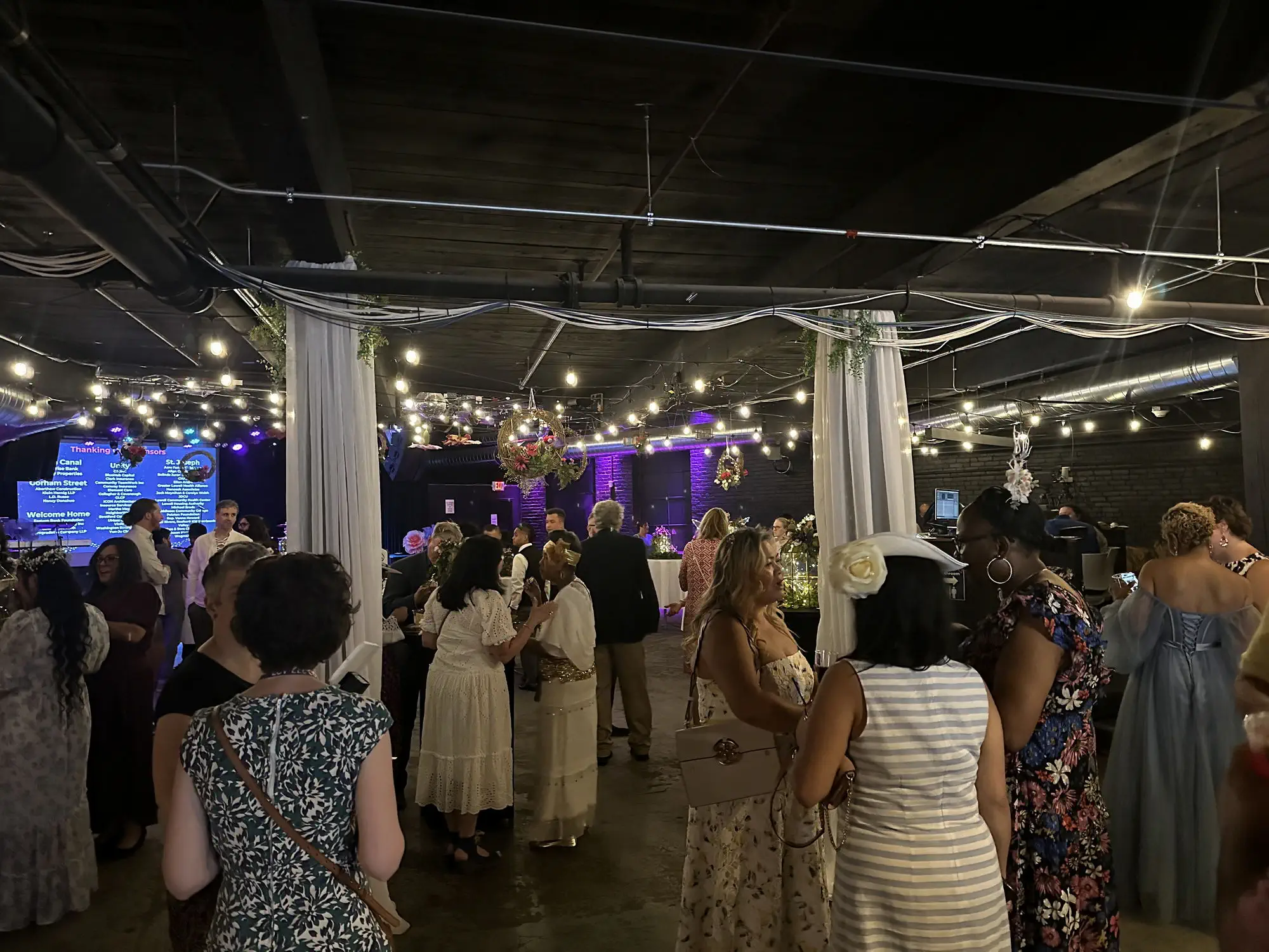 Guests at a private party beneath string lights and draped fabric at Taffeta Music Hall