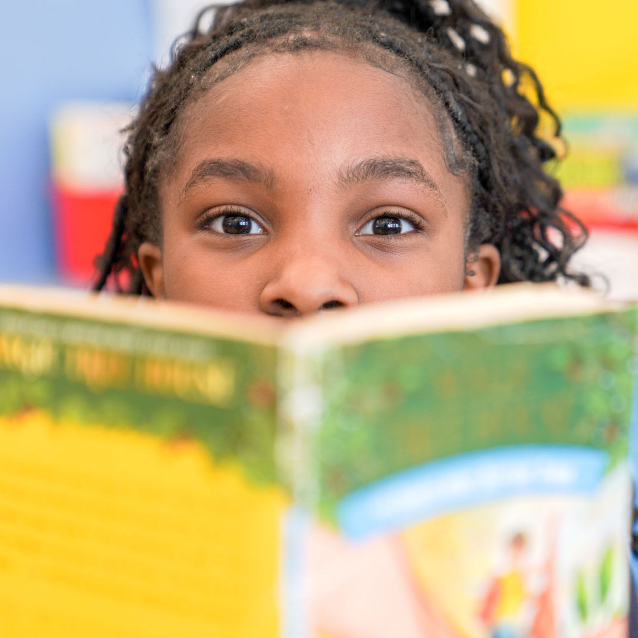 Student peeks over an open book in the classroom