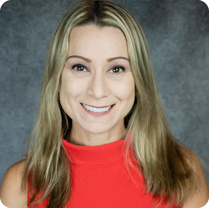 Smiling woman in red top with long blonde hair, professional headshot on gray background