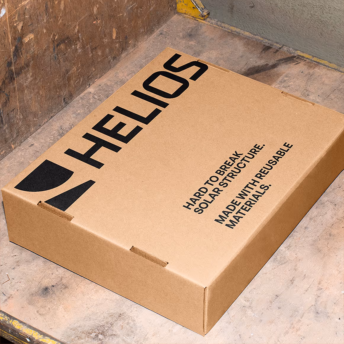 Cardboard box labeled Helios with text stating it has a hard to break solar structure and is made with reusable materials.