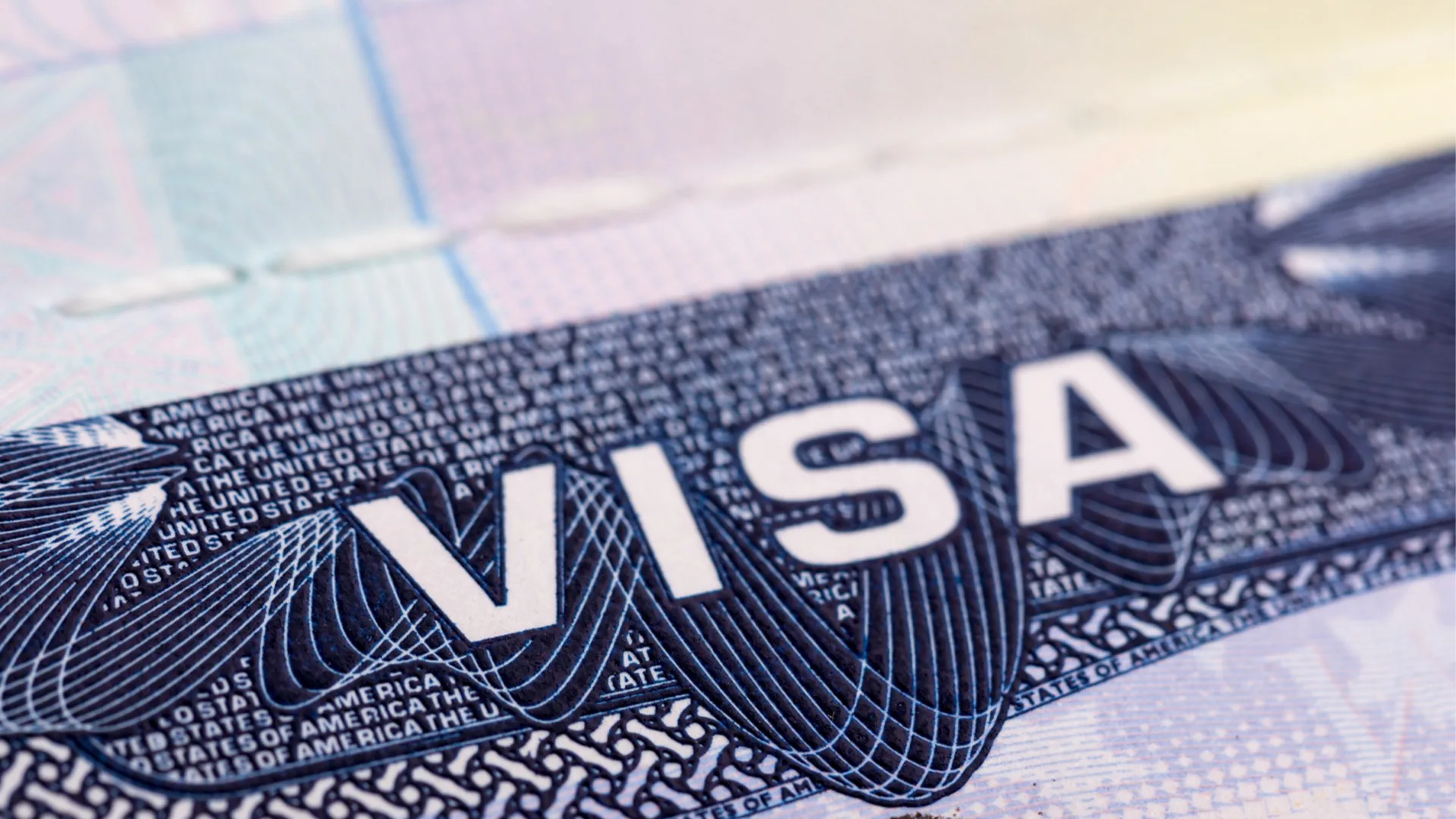 Close-up of a US visa document showing the word "VISA" with security features and intricate engravings.